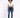 A model wearing a white cropped top and blue skinny jeans, paired with white sneakers, standing against a light backg...