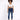 A model wearing a white cropped top and blue skinny jeans, paired with white sneakers, standing against a light backg...