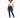 A model with curly hair wears a white cropped top and dark blue skinny jeans, paired with white sneakers.