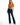 A woman poses in a cropped, rust-colored top tied at the waist, paired with dark flared jeans and heels.