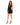 A model poses in a fitted black dress with an off-the-shoulder design and lace-up detailing, paired with strappy heels.