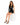 A woman sits on a white pedestal wearing a black dress with a lace-up front and one long sleeve, paired with black he...
