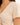 Close-up of a light beige top featuring a deep V-neck and gathered detailing at the front.