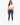 A woman stands confidently in a white cropped top and fitted blue jeans, paired with white sneakers.