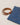 A brown belt with a silver buckle placed beside folded blue denim jeans on a light fabric background.