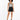 A model with curly hair wears a patterned tank top and high-waisted black shorts, paired with black sneakers.