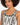 Close-up of a model wearing a patterned bodysuit with a scoop neckline and bold black and white designs.