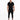 A man stands confidently in a black short-sleeve overall with tapered legs and stylish sneakers.