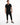 A man stands confidently in a black short-sleeve overall with a relaxed fit and drawstring waist, paired with stylish...