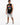 A man stands wearing a sleeveless black shirt with colorful graffiti-style text, paired with distressed gray shorts a...