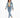 A woman walks confidently in a cropped denim jacket, fitted green top, and light blue jeans paired with white sneakers.