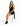 A model sits on a stool wearing a black halter dress with a deep neckline and stylish black ankle boots.