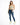 A woman stands confidently in a light green cropped top, distressed blue jeans, and white sneakers with green accents.