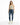 A woman stands confidently in a light green crop top, distressed blue jeans, and white sneakers with neon accents.