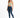 A woman stands confidently in a light green cropped top and dark blue skinny jeans, paired with white sneakers.