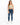 A model wearing a fitted, light green crop top paired with distressed blue skinny jeans and white sneakers.