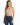 A woman wearing a light green cropped top with thin straps paired with distressed blue jeans.