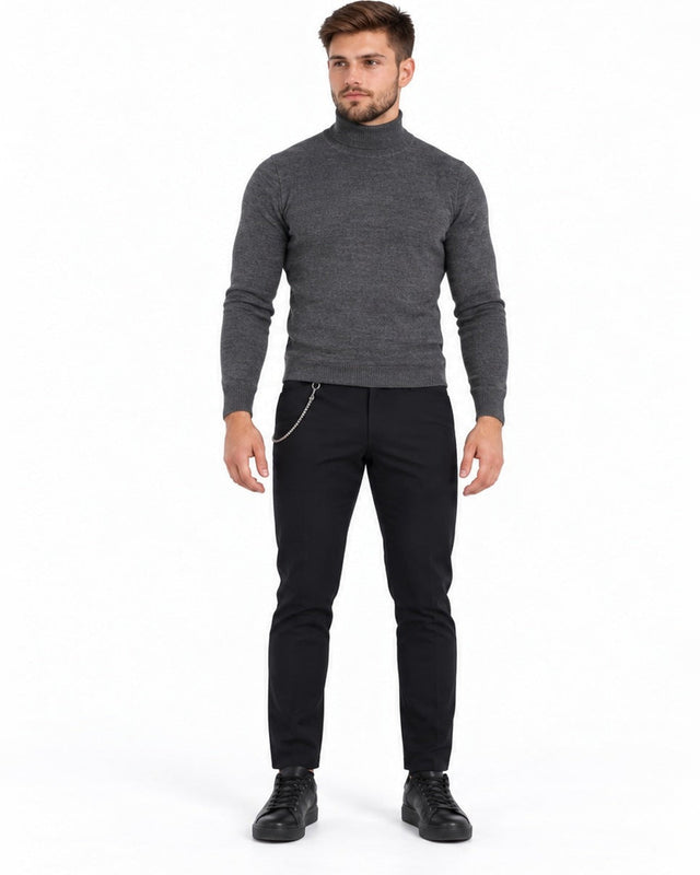 A man stands confidently in a fitted gray turtleneck sweater and black pants, paired with black sneakers.