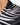 Close-up of a collared shirt featuring a black and white leaf pattern with a smooth, shiny fabric texture.