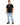 A man stands wearing a black t-shirt with a graphic design, paired with light blue jeans and black sneakers.