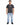A man stands wearing a dark gray t-shirt with a printed design, paired with light blue jeans and black shoes.