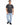 A man stands wearing a dark gray t-shirt with a printed design, paired with light blue jeans and black sneakers.