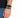 A close-up of a hand wearing a black watch and a beaded bracelet with alternating black and gray beads.