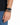 A close-up of a hand wearing a black watch and a beaded bracelet with alternating black and gray beads.