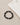 A circular bracelet featuring matte black beads and metallic geometric accents, placed beside a folded light-colored...