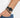 A close-up of a wrist featuring a black beaded bracelet paired with a sleek black watch.