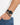 A close-up of a wrist featuring a black beaded bracelet paired with a sleek black watch.