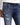 Close-up of distressed blue jeans featuring a silver chain attached to the belt loop, styled with a white long-sleeve...