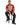 A man sits on a black stool wearing a maroon t-shirt with bold white text and black jeans, paired with black sneakers.