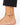 Ankle bracelet featuring black beads and a gold peace symbol charm, worn on a bare foot.