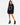 A woman stands in a black oversized sweatshirt featuring a circular white text design, paired with black heeled boots.