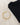 A gold bracelet featuring a crescent moon and star charms, placed beside a folded black shirt on a light background.