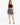 A model wears a black crochet crop top paired with a flowy black and white patterned skirt and strappy heels.