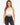 A model wearing a white crochet halter top with a scalloped hem, paired with black high-waisted jeans.