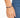 A close-up of a hand wearing a beaded bracelet featuring dark blue and gold accents against denim fabric.