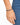 A close-up of a hand wearing a beaded bracelet featuring dark blue and gold accents against denim fabric.