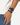 A braided black bracelet worn alongside a sleek black watch on a person's wrist.
