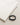 A black braided bracelet rests beside a folded light-colored t-shirt on a textured surface.