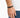 A close-up of a hand wearing a black beaded bracelet with a sleek clasp, set against a light background.