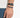 A close-up of a hand wearing a colorful beaded bracelet alongside a black watch.