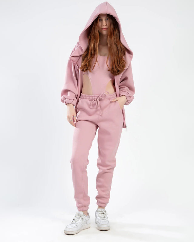 A model wearing a pink hooded sweatshirt and matching joggers, styled with white sneakers.