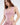 A model poses in a light pink bodysuit with cut-out sides, paired with matching pants.