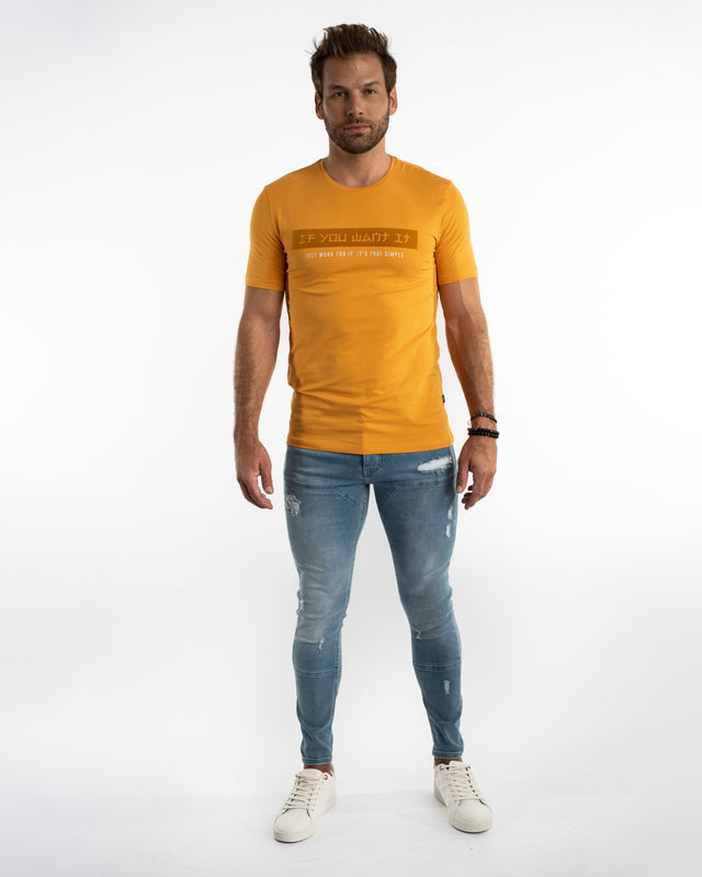 Model wearing Jairo Blue Washed Jeans with biker-style stitching, distressing, and a mustard yellow streetwear t-shirt.