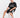 A man sits on a white cube wearing a black graphic t-shirt and black shorts with a white number design.