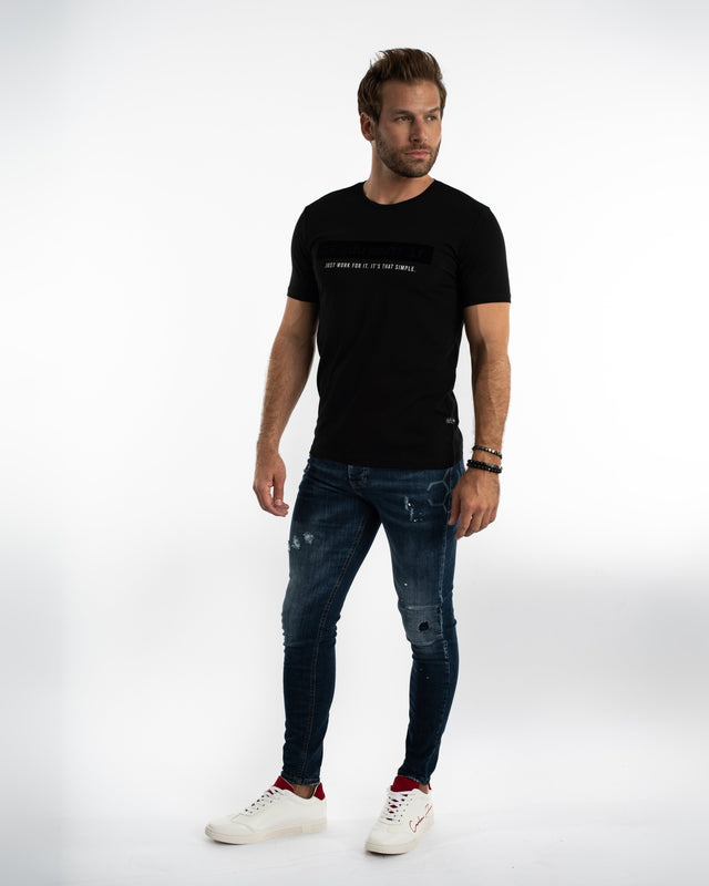 Model in Carbon Jaxx blue washed denim with distressed detailing, styled with a black tee and sneakers.