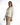 Model in Rhea white denim streetwear jacket with a rope drawstring belt and wooden buttons against a studio backdrop.